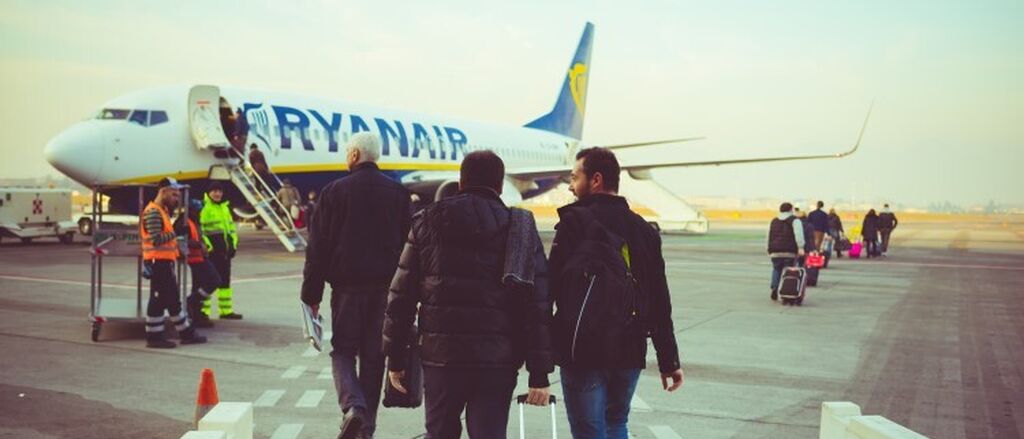 Back view of people carrying luggage boarding on a Ryanair plane resized 750