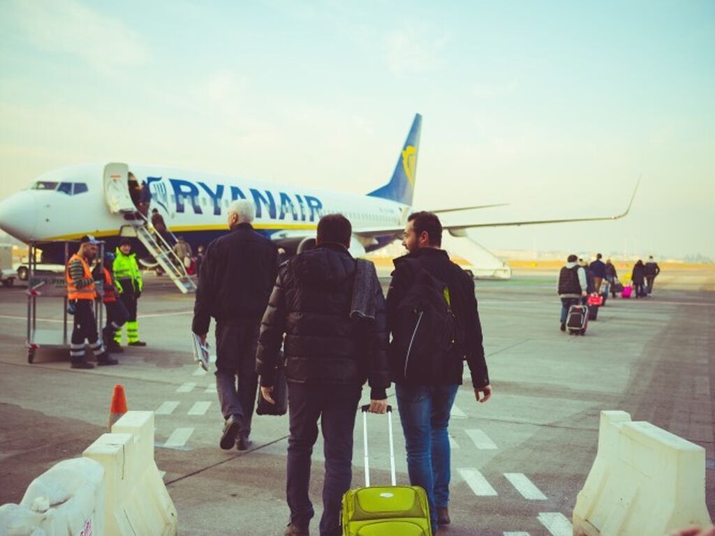 Back view of people carrying luggage boarding on a Ryanair plane resized 750